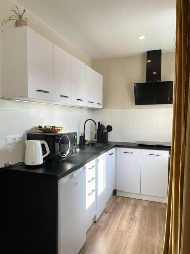 a kitchen with white cabinets and a black counter top at Fashion Apartment in Narva