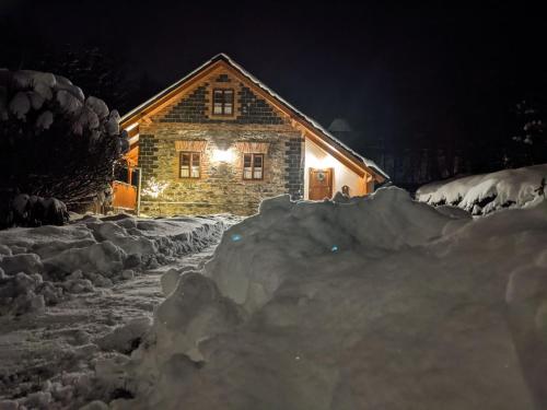 Chalupa u Anenské في Žďárský Potok: كابينة خشب في الثلج في الليل