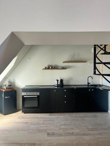 a kitchen with black cabinets and a staircase in an attic at Appartement neuf, centre-ville in Argenton-sur-Creuse