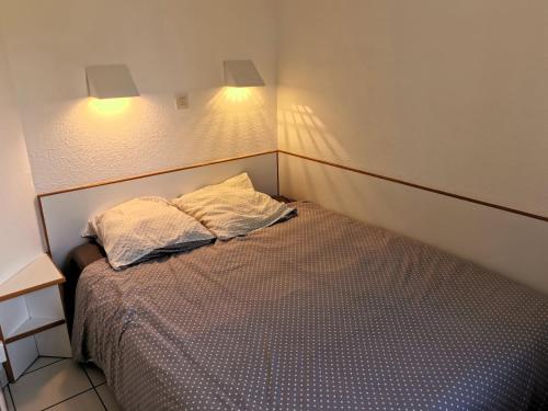 une chambre avec un lit avec deux oreillers dessus dans l'établissement ARCHIPEL ABBA piscine chauffee, à Saint-Hilaire-de-Talmont