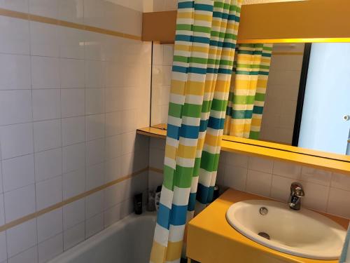 une salle de bain avec un lavabo et un rideau de douche dans l'établissement ARCHIPEL ABBA piscine chauffee, à Saint-Hilaire-de-Talmont