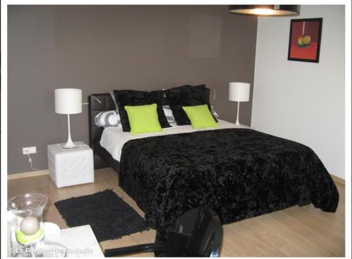 ein Schlafzimmer mit einem großen Bett mit grünen Kissen in der Unterkunft Le Pavillon de Nathalie in Isles-sur-Suippe