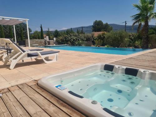 a hot tub sitting on a deck next to a pool at Tiny House Roulotte in Cuges-les-Pins