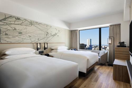 2 łóżka w pokoju hotelowym z dużym oknem w obiekcie Courtyard by Marriott Nagoya w mieście Nagoja