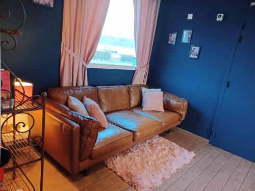 - un canapé en cuir brun dans un salon avec une fenêtre dans l'établissement Auberge La Péniche, à Pierrefitte-sur-Loire