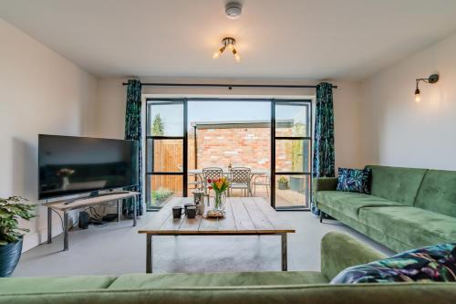 Una sala de estar con un sofá verde y una mesa. en Norton Coach House, en Cheltenham