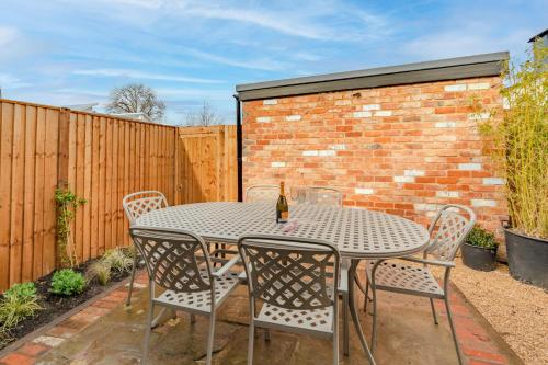 a patio table with chairs and a bottle of wine at Norton Coach House in Cheltenham