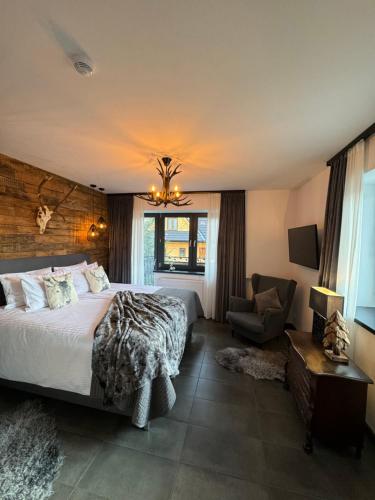 a bedroom with a bed and a chair in it at Framptons Apartments Garden & Spa - Dla dorosłych i dzieci 12 plus - Adults and children 12 plus in Murzasichle