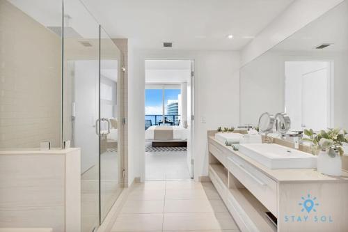 a white bathroom with two sinks and a shower at Oceanfront View - Balcony - Hot Tub - Gym in Hollywood