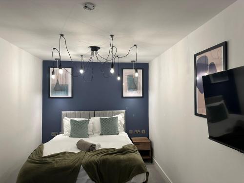 a bedroom with a large bed with blue walls at Newark House Premium Apartments by DH ApartHotels in Peterborough