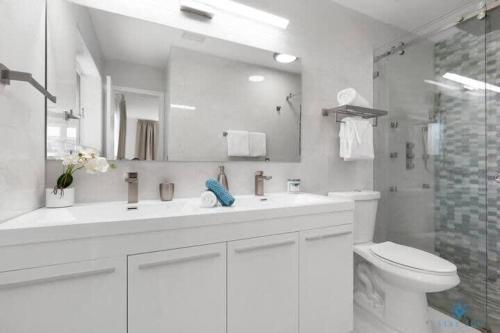 een witte badkamer met een wastafel en een toilet bij Just minutes driving to the Beach, Amazing Pool in Hallandale Beach