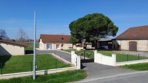 a fence in front of a house with a tree at Gite à la campagne bergeracois in Bergerac