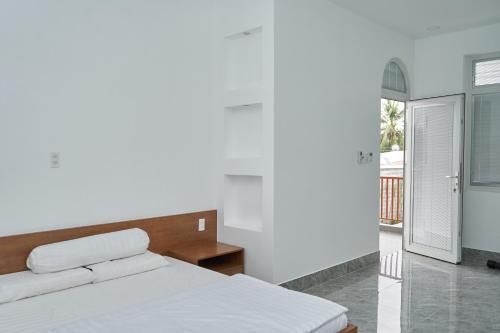 a white bedroom with a bed and a window at Green Villa - Ngôi Nhà Chung in Can Tho
