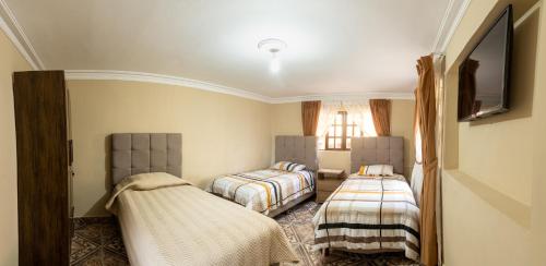 a bedroom with two beds and a flat screen tv at Casa Martinez in Sucre