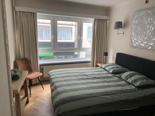 ein Schlafzimmer mit einem Bett, einem Schreibtisch und einem Fenster in der Unterkunft Centraal gelegen gezellig verblijf met groot terras in Ostende
