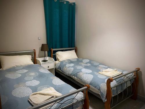 a bedroom with two beds and a blue curtain at City Center Apartments in Mellieħa
