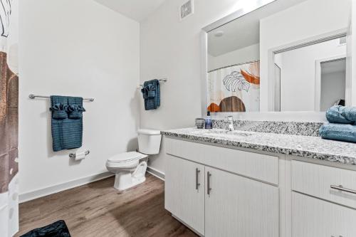 a white bathroom with a toilet and a sink at Sleek Modern Gateway 10 Min to Parks Pets Allowed in Orlando