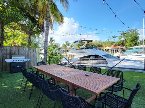 a wooden table and chairs with a boat in a marina at Waterfront - Kayak & Paddleboards - Firepit - Pool in Miami