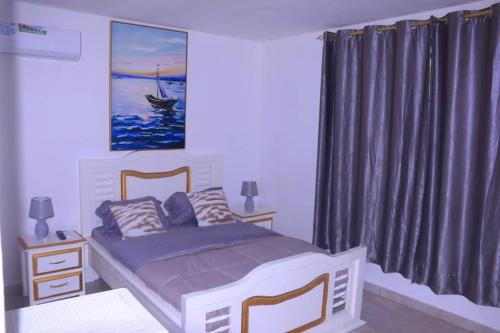 1 dormitorio con 1 cama y una pintura de un barco en Résidence reine lumière en Libreville