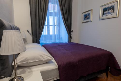1 dormitorio con 1 cama con manta morada y ventana en Little Vienna Silver Apartment, en Varaždin