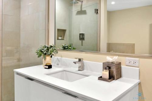 ein Badezimmer mit einem weißen Waschbecken und einem Spiegel in der Unterkunft Front Bay View Terrace Rooftop Pool Near Beach in Hollywood