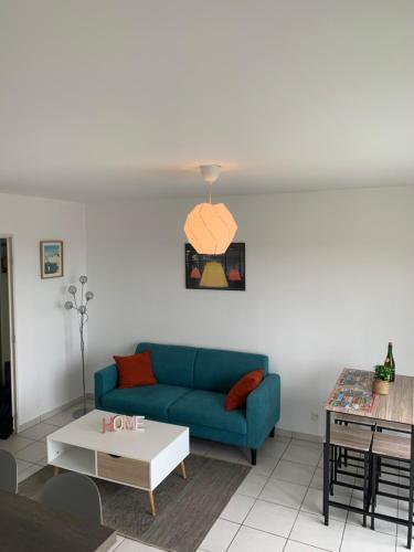 uma sala de estar com um sofá azul e uma mesa em Appartement T2 dernier étage em Touques