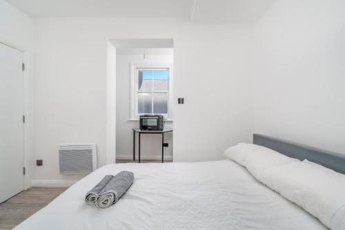 a white bedroom with a bed with a towel on it at Cozy Studio Flat- Dalston Central in London