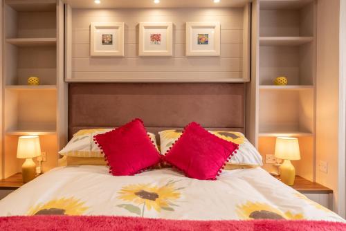 a bedroom with a bed with two red pillows at 62 Meadow View in Ilfracombe