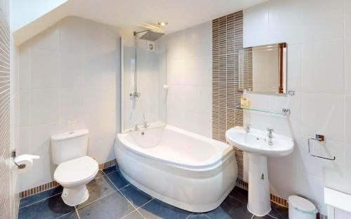 a bathroom with a tub and a toilet and a sink at CROYDE THATCHERS HIDEAWAY 2 Bedrooms in Croyde