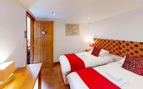 a hotel room with two beds with red and white sheets at CROYDE THATCHERS HIDEAWAY 2 Bedrooms in Croyde