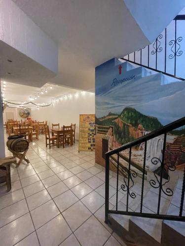 a restaurant with tables and chairs and a mural on the wall at Hotel towi in Creel