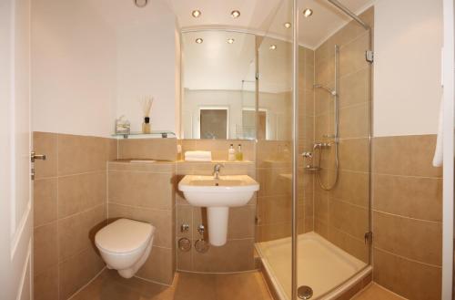 uma casa de banho com um WC, um lavatório e um chuveiro em Meer & Strand - Haus Meeresstrand Ferienwohnung 213 em Scharbeutz