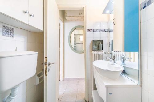 a white bathroom with a sink and a mirror at Corfu Central Casa Seniora Stamy in Ágios Rókkos