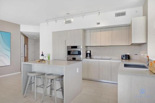 a kitchen with white cabinets and bar stools at High Floor with Stunning Views, Amazing Pools in Hollywood
