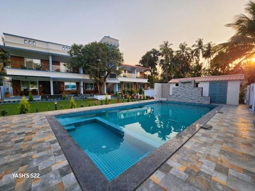 a swimming pool in front of a house at Basil Leaf Resort in Alibag