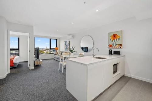 a white kitchen with a sink and a living room at Urban Elegance Stature Southbank in Melbourne