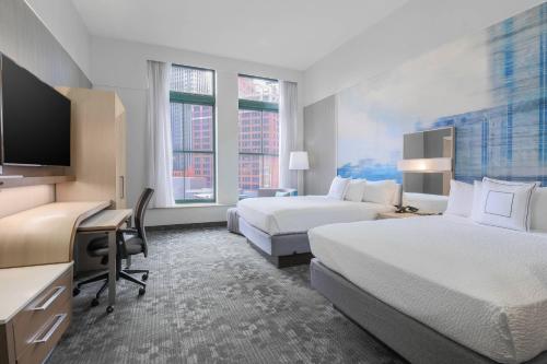 a hotel room with two beds and a desk at Courtyard by Marriott Pittsburgh Downtown in Pittsburgh