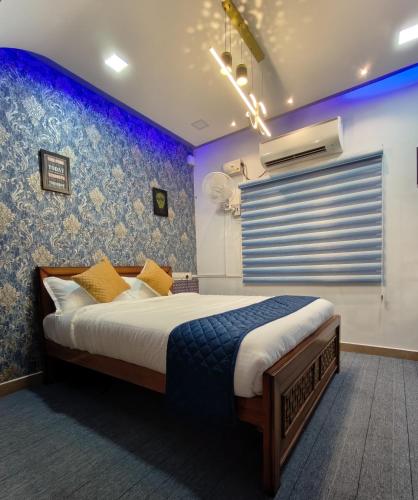 a bedroom with a bed and a blue wall at Sunshine Villa & Homestay in Tiruchirappalli