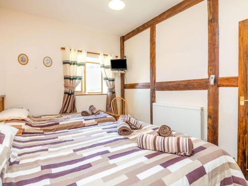 two beds in a room with wooden beams at The Carthouse in Hereford