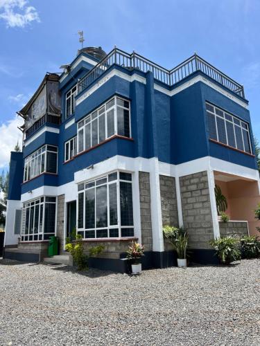 niebiesko-biały budynek z roślinami przed nim w obiekcie The Fairway Residence w mieście Nyeri