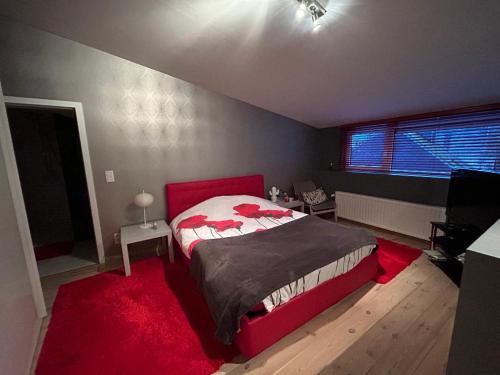a bedroom with a red bed and a red rug at Chambre chez Françoise in Spa