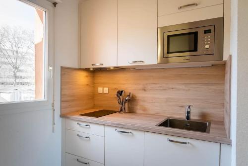 une cuisine avec un évier et un micro-ondes dans l'établissement La Terraza, T2 avec Clim, Parking, Port Marianne, à Montpellier