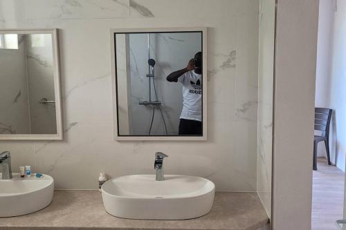3 master bedrooms All-in-one في روسو: رجل يلتقط صورة لمغسلة الحمام