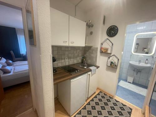 una pequeña cocina con armarios blancos y fregadero en Gemütliches Apartment My Little Black Forest en Freiburg im Breisgau