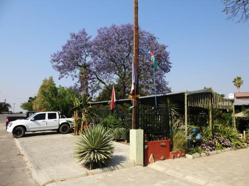 a white truck parked in a parking lot with purple flowers at ANSTA SELF CATERING Home in Outjo