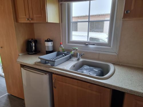 a kitchen counter with a sink and a window at promenade direct beach access in Ingoldmells