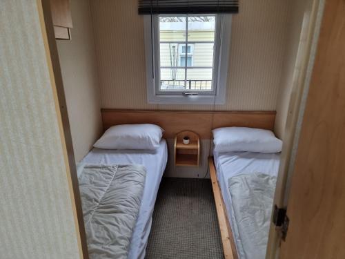 two beds in a small room with a window at promenade direct beach access in Ingoldmells