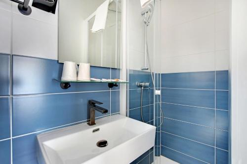 a bathroom with a white sink and blue tiles at Altona in Paris