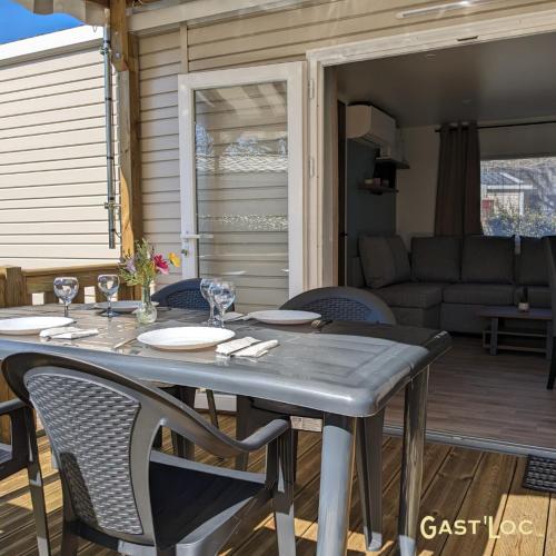 une table et des chaises sur une terrasse avec un canapé dans l'établissement Le Rêve bleu MOBIL HOME 49 3 CHAMBRES, à Gastes