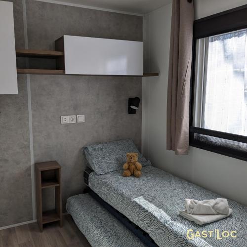 - un ours en peluche assis sur un lit dans une chambre dans l'établissement Le Rêve bleu MOBIL HOME 49 3 CHAMBRES, à Gastes